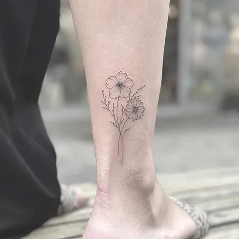 Fineline tattoo of a bouquet with an anemone and a daisy on the calf