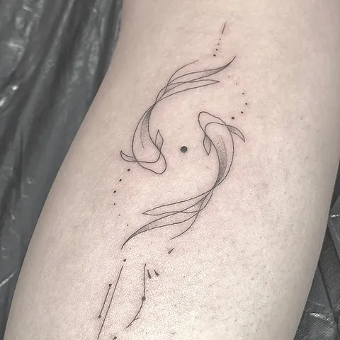Fineline tattoo of two koi fish swimming around each other on the upper arm