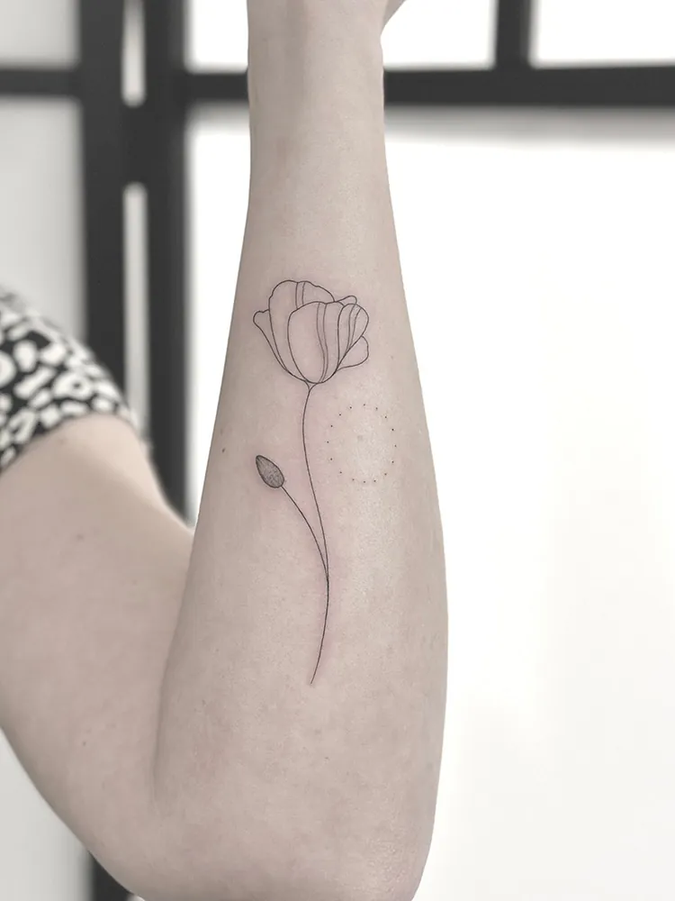 Fineline tattoo of a tulip with a long stem on the forearm