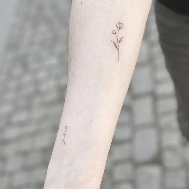 Lille blomst tatoveret på arm