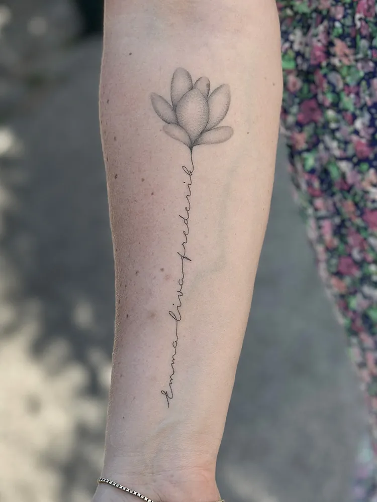 Fineline tatovering af blomst med tekst på underarm