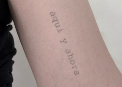 Helet fineline tekst-tatovering med spansk citat på underarm