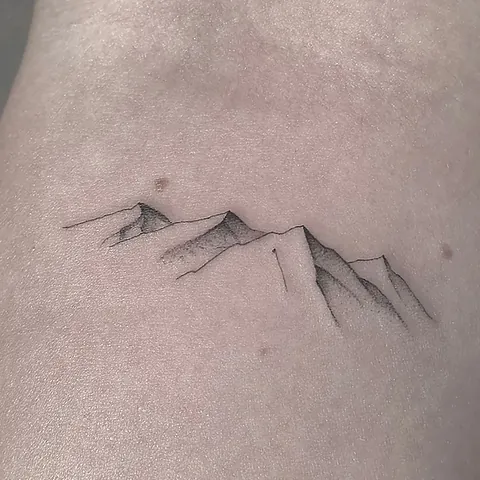 Fineline tattoo of a mountain range with shading on the back