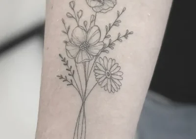Fineline tatovering af blomsterbuket med valmue og margerit på overarm