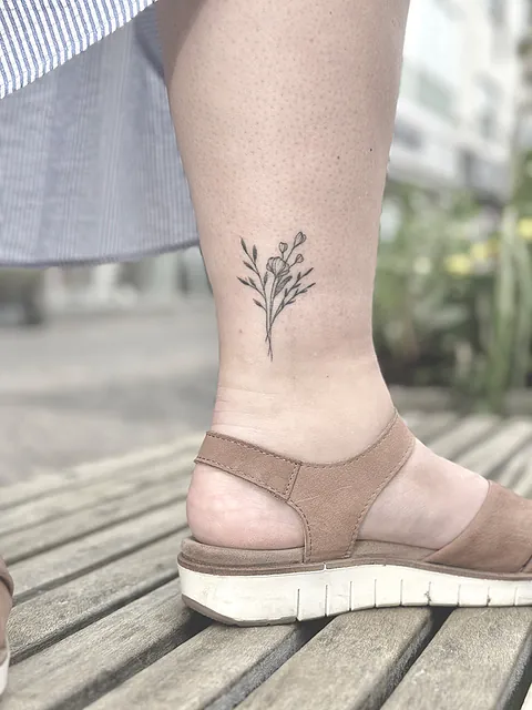 Fineline tatovering af blomstergren på lægben