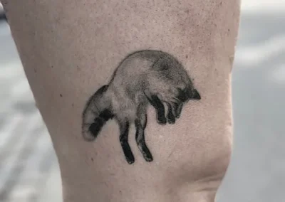 Skyggelagt tatovering af en ræv i bevægelse på overarm