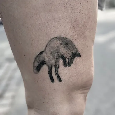 Skyggelagt tatovering af en ræv i bevægelse på overarm