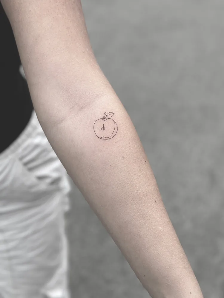 Lille fineline tatovering af et æble på underarm