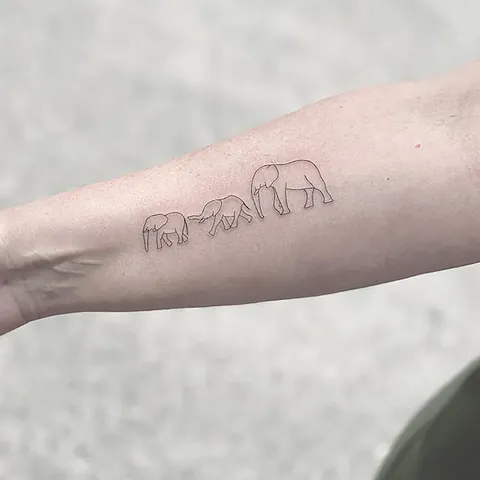 Fineline tatovering af en elefantfamilie der går på række på underarm