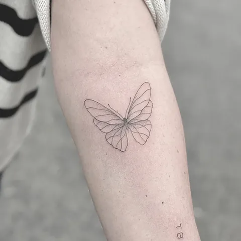 Fineline tatovering af sommerfugl med detaljerede vinger på underarm