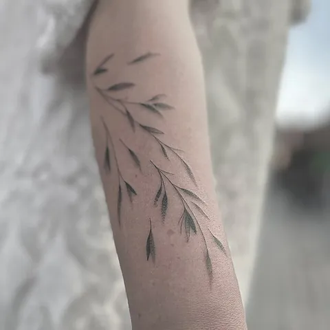 Fineline tatovering med grene og blade der snor sig ned ad armen