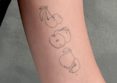 Helet fineline tatovering af kirsebær og æbler på underarm