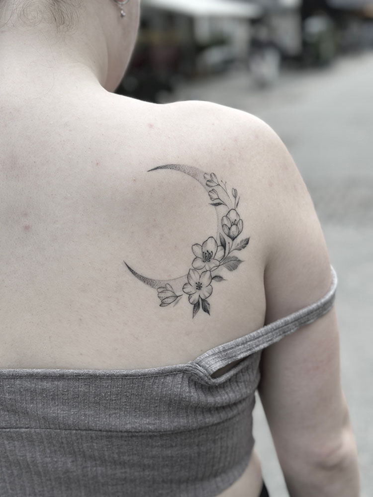 Fineline tatovering af halvmåne med blomster på skulder