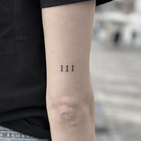 Fineline tattoo of the number 111 on the forearm
