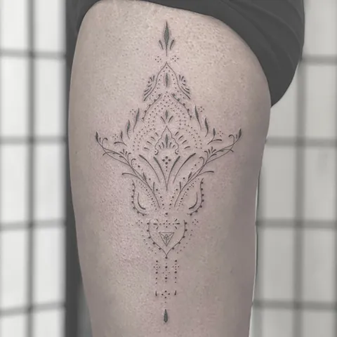Ornamenteret fineline tatovering med symmetrisk mønster på forsiden af låret