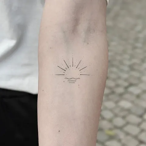 Fineline tattoo of a sunrise with rays on the forearm