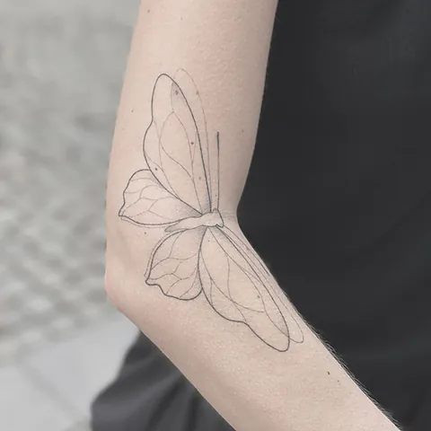 Fineline tatovering af sommerfugl i omrids ved albuen