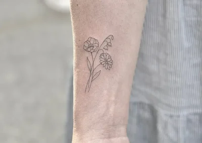 Fineline-tatovering med to små blomster på underarmen