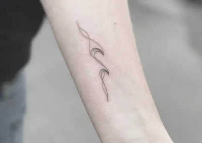 Fineline-tatovering med et bølget, abstrakt motiv på underarmen
