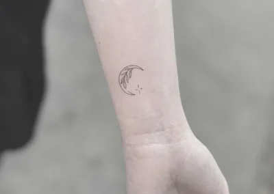 Lille fineline-tatovering af en måne på håndleddet