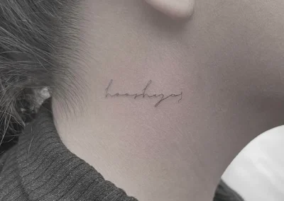 Fineline-tatovering med håndskrift på halsen bag øret