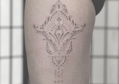 Ornamental fineline-tatovering med mønster og prikker på låret