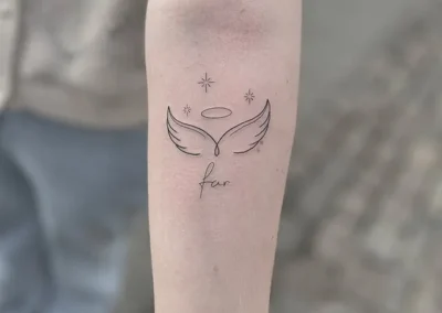 Fineline-tatovering med englevinger, glorie og ordet far på underarmen