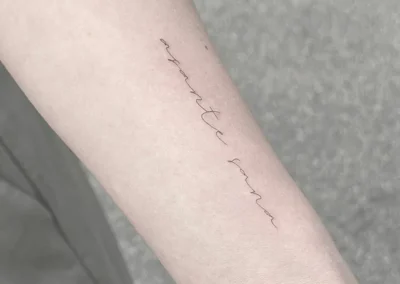 Fineline-tatovering med håndskrift op langs underarmen