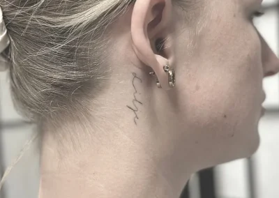 Helet fineline-tatovering med håndskrift på halsen bag øret