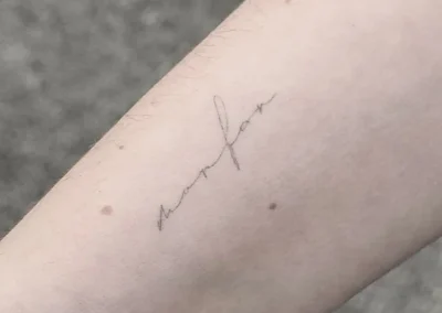 Helet fineline-tatovering med håndskrift på underarmen