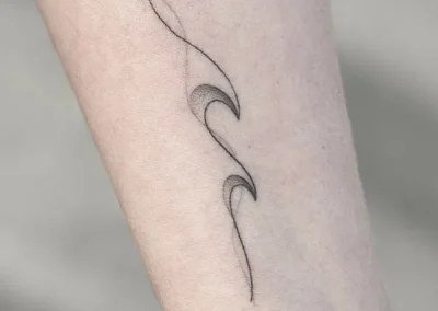 Helet fineline-tatovering med et bølget, abstrakt motiv på underarmen