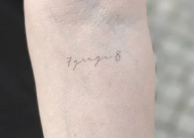 Helet fineline-tatovering med håndskrift på overarmen