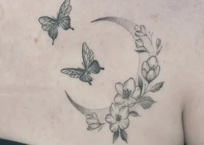 Helet fineline-tatovering med en måne, sommerfugle og blomster på ryggen