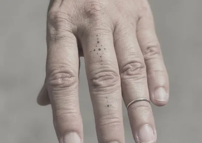 Helede fineline-tatoveringer med små prikker på fingrene