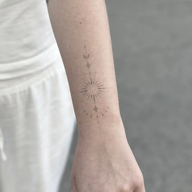 Healet – sol og måne på underarm Helet fineline-tatovering med en sol med stråler og en måne på underarmen