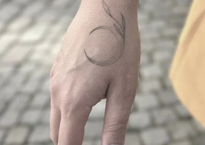 Helet fineline-tatovering af en måne på håndryggen