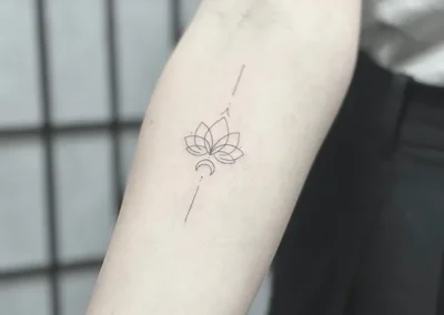 Fineline-tatovering med et lille lotusornament på underarmen