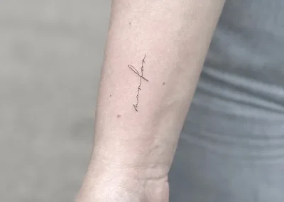 Fineline-tatovering med håndskrift på underarmen