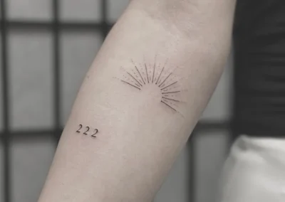Fineline-tatovering med en solopgang og tallet 222 på underarmen