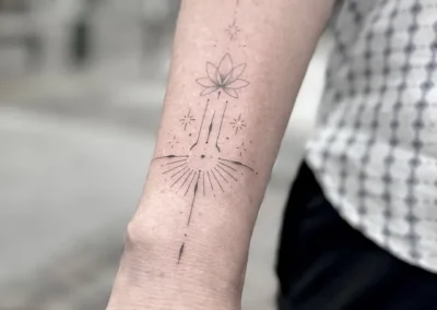 Fineline-tatovering med en stjerne og stråler ned langs underarmen