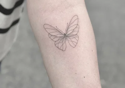 Fineline-tatovering af en sommerfugl på underarmen